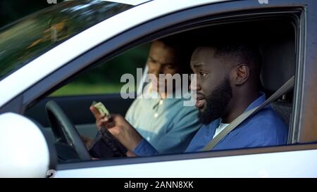 Père en colère en donnant l'argent de poche à son sitting in auto, conflit parent Banque D'Images