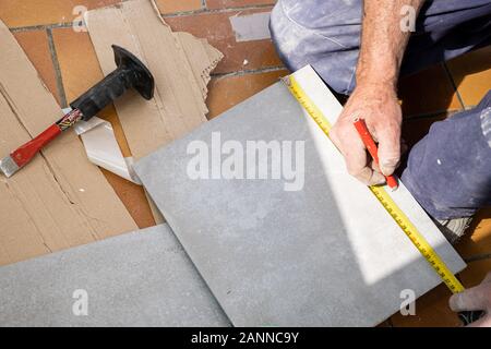 Le carreleur mesure les carreaux avant qu'elle coupe Banque D'Images