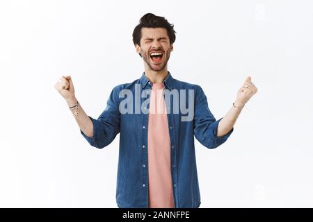 Très heureux joyeux barbu beau hurler de bonheur à voix haute, fermer les yeux et serrer les poings, les mains de la pompe jusqu'à partir de la joie, sentiment de chance de gagner Banque D'Images