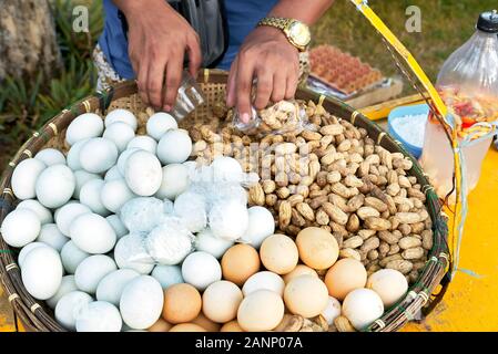 Close-up d'arachides à la vapeur et blanc et brun oeufs durs, joliment présenté dans un plateau en bambou d'origine, vendu par un vendeur de rue aux Philippines Banque D'Images