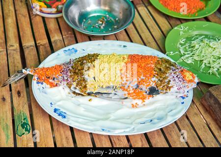 Thon frit recouvert d'oignons, carottes et fromage présenté sur une assiette décorée avec des tranches de concombre. C'est un plat originaire des Philippines Banque D'Images