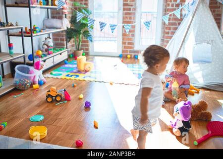 Les bambins adorables jouant autour de beaucoup de jouets à l'école maternelle Banque D'Images