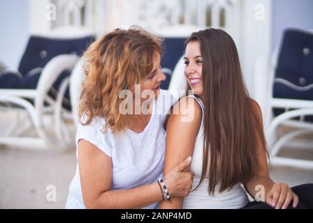 Belle Mère et fille assis à terrasse hugging and smiling Banque D'Images