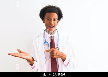 Young african american man wearing sthetoscope médecin isolé sur fond blanc étonné et souriant à la caméra tout en se présentant avec la main et p Banque D'Images