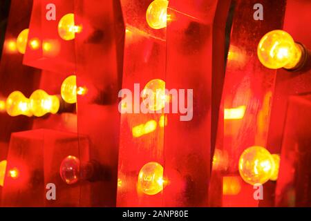 Close-up of a allumé en jaune ampoules colorées attachées à une très forte faite de l'arrière-plan rouge en plastique acrylique Banque D'Images