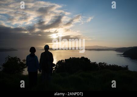 Couple watching sunrise at réserve historique de Tapeka, Russell, Bay of Island Banque D'Images