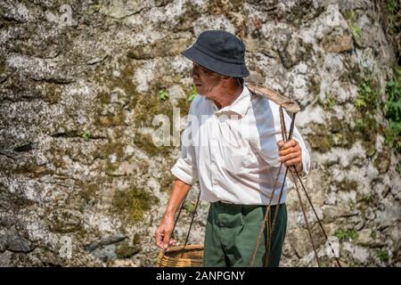 Pingan, Chine - Août 2019 : vieux Chinois transportant une charge lourde de fruits en vente jusqu'aux pentes escarpées en chemin, Pingan Longji terrasses de riz, l'Hepi Banque D'Images