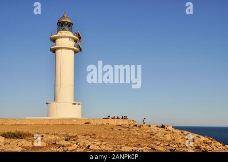 Groupe de gens assis au pied du Cap de Barbaria phare de la Berbería cape à Formentera (Pityuses, Îles Baléares, Mer Méditerranée, Espagne) Banque D'Images