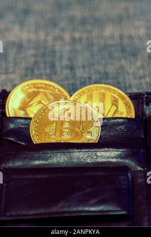 Pièce de monnaie crypto dans Etui en cuir sur fond gris ethereum bitcoin litecoin. bien-être financier. photo verticale. Banque D'Images