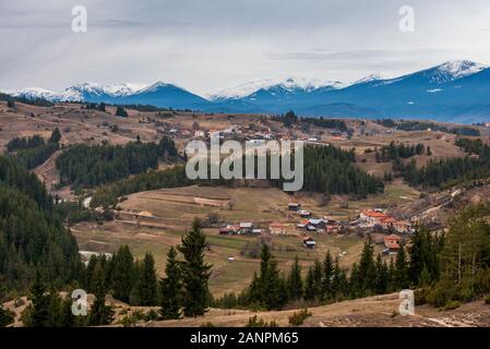 Village bulgare en Konarsko Rhodopes en face de pics enneigés Rila Banque D'Images