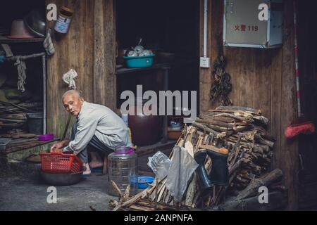 Pingan, Chine - Août 2019 : pauvre vieux faisant corvées maison à l'extérieur de sa cabane en bois dans la région de Ping An, Village Longji terrasses de riz, Province du Guangxi Banque D'Images