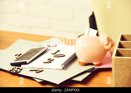 Des papiers différents avec des nombres, cahier, rose cochon Piggy Bank et du téléphone cellulaire sur la table en bois brun Banque D'Images