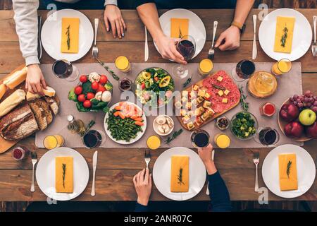 Les gens assis à la maison derrière la table avec de la nourriture Banque D'Images