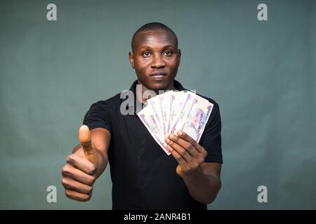 un jeune homme africain qui tient de l'argent, se moque Banque D'Images