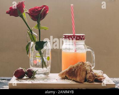 Petit déjeuner romantique avec jus d'orange, roses et fraises Banque D'Images