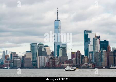 Lower Manhattan New York City Skyline photographié de Liberty Island en face de l'Hudson River avec un ferry en bateau et Banque D'Images