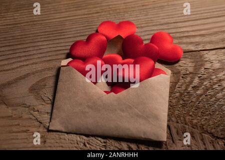 Lettre d'amour de Saint-Valentin, enveloppe avec coeur rouge tas propagation sur fond de bois. Banque D'Images
