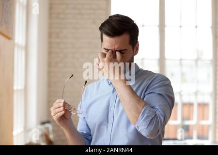 Fatigué businessman taking off lunettes, souffrant de la fatigue oculaire Banque D'Images