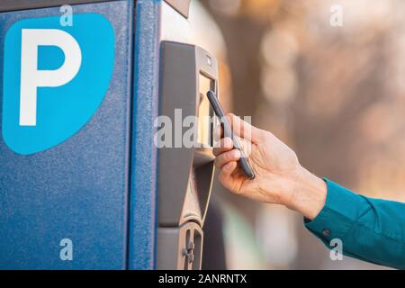 Conducteur paie pour l'espace de stationnement de voiture téléphone paiement sans contact Banque D'Images