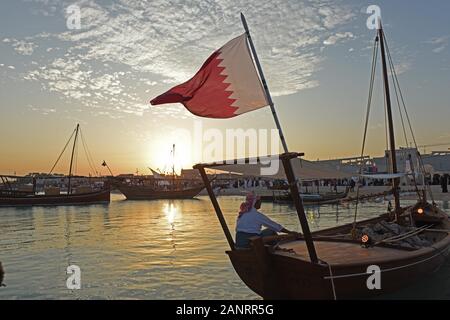 Les hommes assis sur le Dhow avec le drapeau du Qatar Katara au coucher du soleil, dhaw traditionnel festival, Doha, Qatar. Banque D'Images