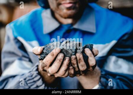 Miner les mains sales holding morceau de mine de charbon Banque D'Images