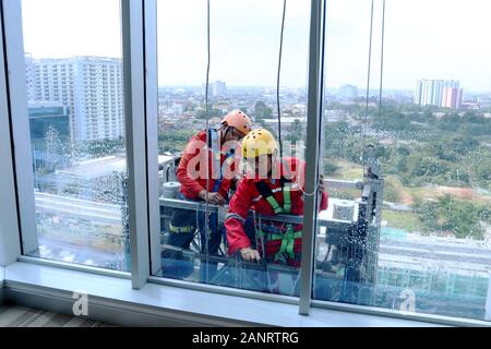 Deux travailleurs qui nettoyaient les fenêtres dans un bâtiment de grande taille à Jakarta, en Indonésie, en Asie Banque D'Images