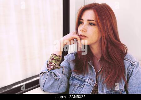 Candide jeune femme regardant par la fenêtre tout en restant assis dans daydraming ou tramway le tramway Banque D'Images