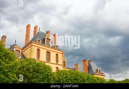 Vue sur le bâtiment Cour des bureaux, qui fait partie du Château de Fontainebleau (Palais de Fontainebleau), sous un ciel nuageux spectaculaire. France. Banque D'Images