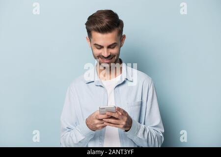 Guy millénaire heureux holding smartphone dans les mains. Banque D'Images