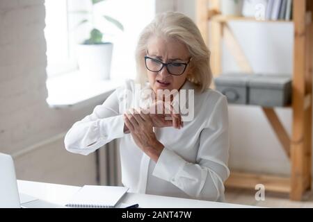 Mature businesswoman touching hand sentiment de douleur au poignet Banque D'Images