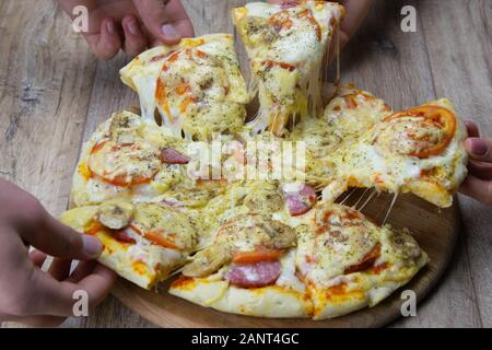 Les gens sont à l'arraché des morceaux de pizza à la mozzarella et les tomates. salami. Top vues Banque D'Images