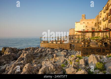 Restaurant en bord de mer dans la vieille ville au coucher du soleil méditerranéen à Cefalu. Le Cefalu historique est une destination touristique majeure de la Sicile. Banque D'Images