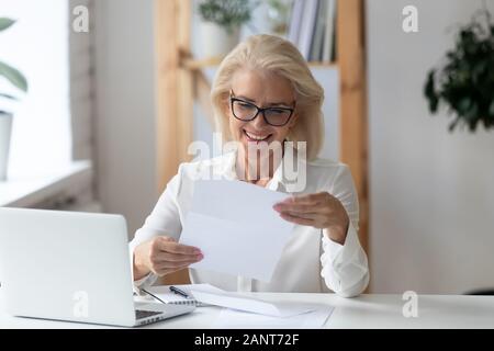 Mature businesswoman holding lettre lecture document papier se sent satisfait Banque D'Images