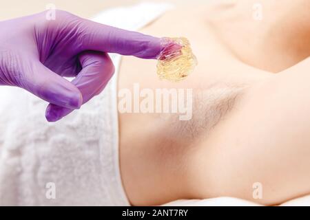 Shugaring concept d'enlèvement de cheveux. Épilation Processus d'underarm fille avec la pâte de sucre en spa salon, fond blanc Banque D'Images