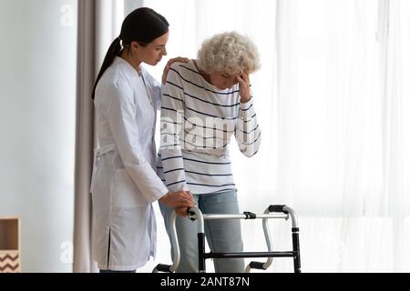 Aider les aidants naturels âgés handicapés femme debout avec walker, sensation de malaise Banque D'Images