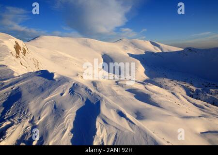 Le soleil qui illumine les pentes enneigées des montagnes. Banque D'Images