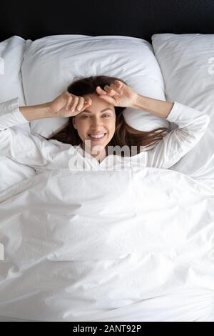 Portrait Vertical happy woman lying on oreiller soft au lit Banque D'Images