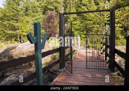 Passerelle en bois peinte marron et turquoise et métal en fer forgé barrière menant à un jardin privé de campagne en été Banque D'Images