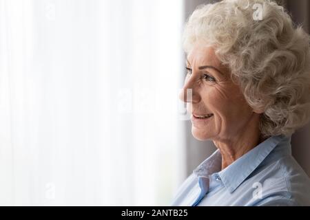 Close up happy smiling woman looking out window, rêvant seul Banque D'Images