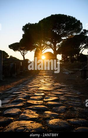 Rome. L'Italie. Ostia Antica. Coucher du soleil sur le Decumanus Maximus, le principe voie romaine dans l'est la moitié d'Ostie. Il s'étend de l'est à l'ouest, à partir de Banque D'Images