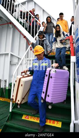 Haikou, Chine. 19 Jan, 2020. Un membre du personnel aide les passagers de transporter des bagages sur un ferry dans le Port de Xiuying Haikou, capitale du sud de la Chine, 19 janvier 2020. Le détroit de Qiongzhou assisté à une ruée vers les voyages comme le Festival de Printemps s'approche. Credit : Guo Cheng/Xinhua/Alamy Live News Banque D'Images