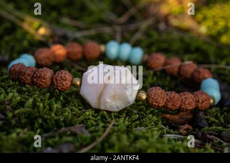 Beau bracelet femme fazeted avec pierre d'opale et graines de Rudraksha sur fond de forêt naturelle Banque D'Images