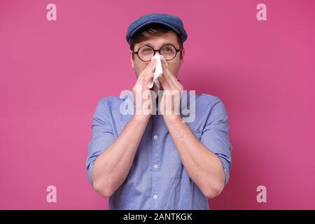 Concept de rhume ou de grippe. Man dans les verres des éternuements en mouchoir, malade. Studio shot Banque D'Images