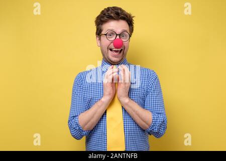 Homme choqué avec nez de clown rouge et jaune tie étant choqué. Premier jour de poisson d'avril. Studio shot Banque D'Images