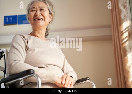 Happy senior asian woman sitting in wheel chair dans sa chambre en maison de soins infirmiers, heureux et souriant Banque D'Images