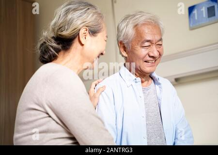 Happy asian senior couple talking in hospital ward Banque D'Images