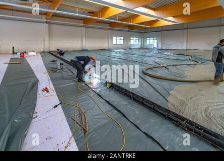 La chape est coulée sur un site de construction à l'intérieur d'un grand bâtiment de l'usine Banque D'Images