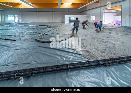 La chape est coulée sur un site de construction à l'intérieur d'un grand bâtiment de l'usine Banque D'Images