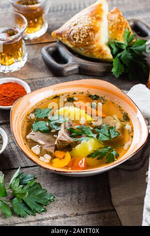 Soupe Asiatique shurpa avec viande et légumes dans la plaque sur le wooned table. Banque D'Images