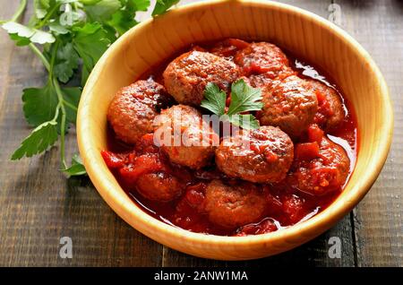 Boulettes frites en sauce tomate dans bol en bois. Vue rapprochée Banque D'Images